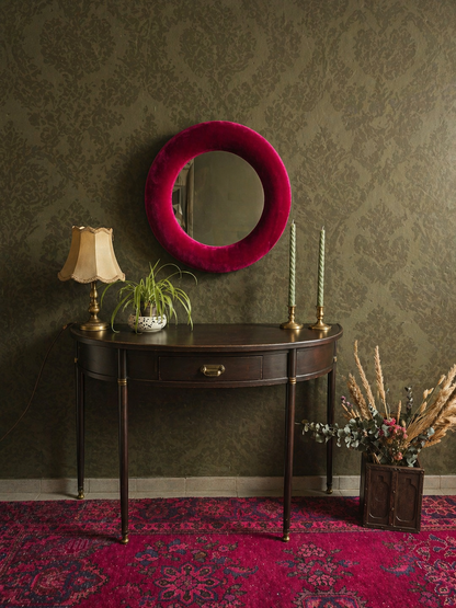 Magenta pink velvet round wall mirror 60cm styled against dark green wall with dramatic contrast